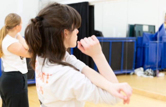 Dancer completes a shoulder stretch, facing away from the camera.