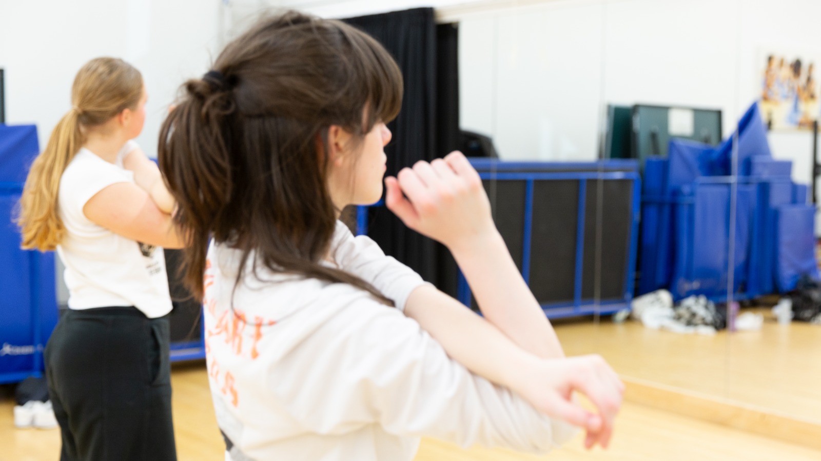 Dancer completes a shoulder stretch, facing away from the camera.